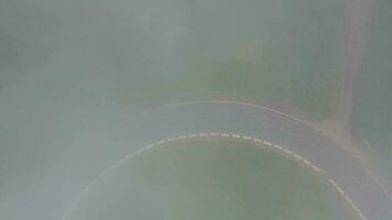 Flying through the clouds over a mountain road surrounded by green vegetation. Cars driving on the road video