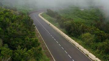 vôo através a nuvens sobre uma montanha estrada cercado de verde vegetação. carros dirigindo em a estrada video