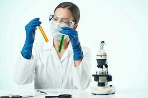 hembra laboratorio asistente vistiendo amarillo lentes químico solución microscopio investigación biotecnología foto