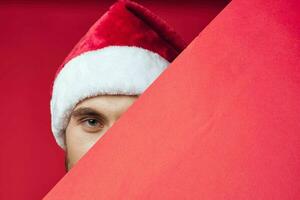 Cheerful man in a santa hat holding a banner holiday red background photo