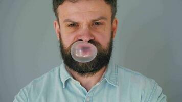 Bearded man chews chewing gum and inflates a bubble out of it. Bad habit concept video