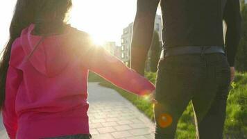 Dad and daughter walk around their area at sunset. Child holds father's hand. Slow motion video