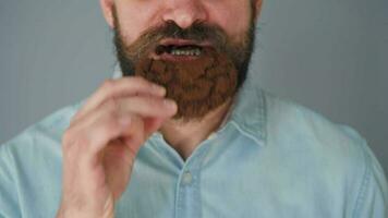 barbudo homem com enrolado acima bigode comendo chocolate lasca biscoitos em uma cinzento parede fundo video