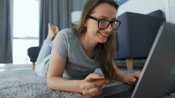 Woman is lying on the floor and working on a laptop. Concept of remote work. video