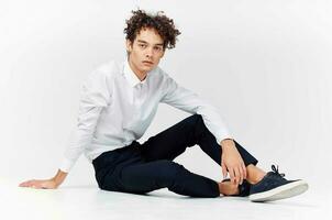 guy in a white shirt sitting on the floor curly hair fashion photo