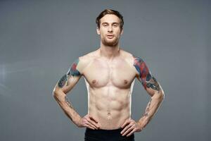 athletic man with pumped up abs tattoos on his arms photo