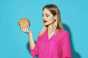 cheerful blonde in a pink shirt hamburger fast food snack blue background photo