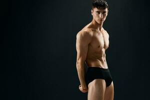 attractive sporty man in dark shorts phasing Studio dark background photo