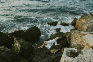 mujer acostado en rocoso costa con grietas en rocoso superficie ver desde encima foto