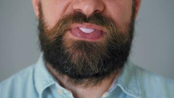 Bearded man chews chewing gum and inflates a bubble out of it. Bad habit concept video