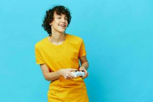 man plays with joystick in yellow t-shirts blue background photo