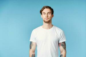 man with tattoos on his arms white t-shirt cropped view blue background photo
