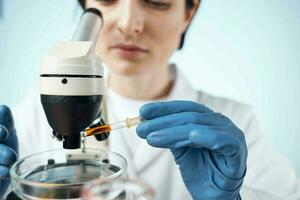 female laboratory assistant looking through a microscope biotechnology science research photo