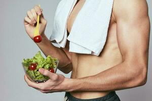 atlético hombre con un mejorado torso toalla en su espalda un plato de ensalada sano comida foto