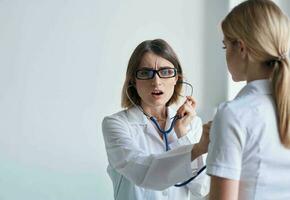 mujer médico con estetoscopio y lentes examina el paciente salud modelo foto