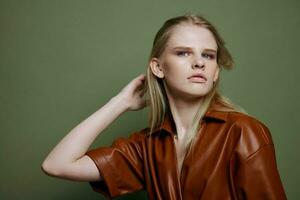 Stylish offer. Headshot portrait of beautiful blonde female model looks at camera posing isolated on over green olive wall photo