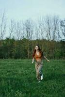 A woman runs in the park on green grass at a workout photo