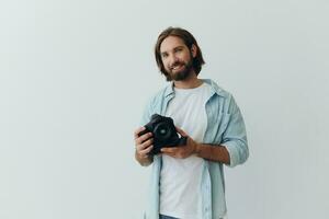 Man hipster photographer in a studio against a white background holding a professional camera and setting it up before shooting. Lifestyle work as a freelance photographer photo