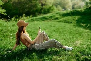 Freelance woman working on her phone against a green summer landscape, the lifestyle of a blogger photo