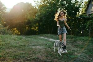 mujer y su fornido perro felizmente corriendo mediante el césped en naturaleza en el parque sonrisa con dientes otoño caminar con mascota, de viaje con un perro amigo foto