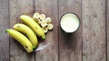 top view of slice of banana glass of milk on table video