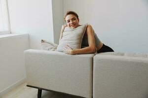 Happy woman smile lying at home on the couch relaxing on a weekend at home with a short haircut hair without filters on a white background, free copy space photo