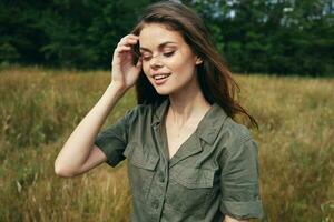 Cheerful woman outdoors in green jumpsuit straightens her hair close-up photo