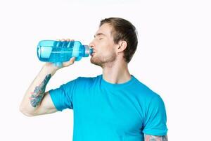 guy athlete drinks water from a bottle on a white background and a blue t-shirt photo