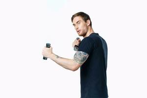 athlete in black t-shirt with dumbbells in hand on white background cropped view photo
