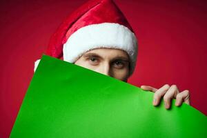 Cheerful man in a santa hat holding a banner holiday red background photo