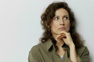 Thoughtful pensive serious unhappy curly beautiful woman in casual khaki green shirt recline on hand looks aside posing isolated on over white background. People Emotions Lifestyle concept. Copy space photo