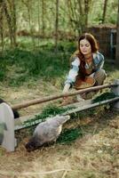 mujer granjero sonrisas y vierte comida para el aves a el pájaro alimentador a el pollo granja foto