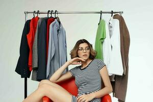 beautiful woman with glasses next to clothes fashion fun retail isolated background photo