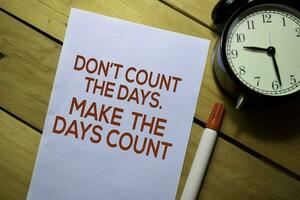 Don't Count The Days. Make The Days Count text on the paper isolated on table background photo