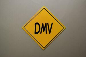 DMV write on a sticky note isolated on office desk. photo