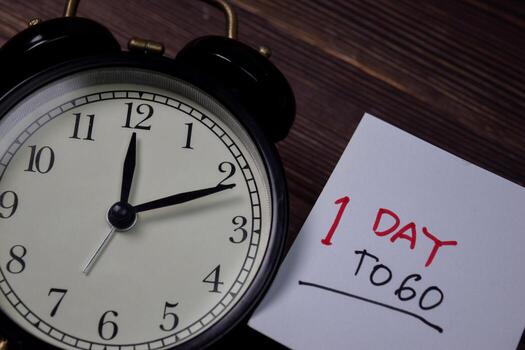 1 Day To Go write on sticky note isolated on wooden table. photo