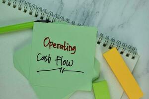 Operating Cash Flow write on sticky note isolated on Wooden Table. photo
