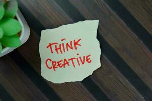 Think Creative write on sticky notes isolated on Wooden Table. photo