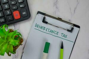 Inheritance Tax write on a paperwork isolated on Wooden Table. medical concept photo