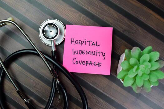 Concept of Hospital Indemnity Coverage write on sticky notes isolated on Wooden Table. photo