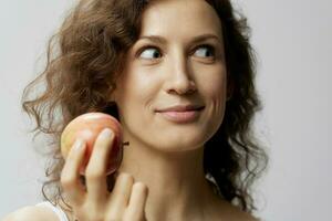 Excited shocked funny curly beautiful woman in basic white t-shirt enjoy apple looks aside posing isolated on over white background. Natural Eco-friendly products concept. Copy space photo