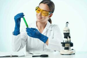 hembra laboratorio asistente vistiendo amarillo lentes químico solución microscopio investigación biotecnología foto