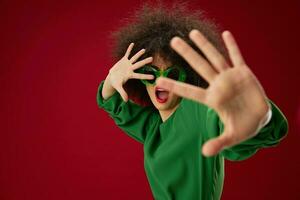 woman with curly hairstyle with sunglasses on a red background emotions photo