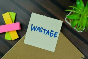 Wastage write on sticky notes isolated on Wooden Table. photo