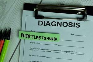 Diagnosis and Phenylketonuria write on a paperwork isolated on wooden table. photo