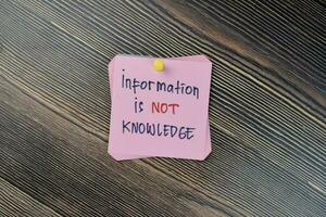 Concept of Information is not knowledge write on sticky notes isolated on Wooden Table. photo