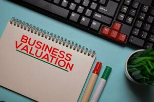 Business Valuation write on a book isolated on office desk. photo