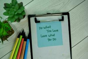 Do What You Love Love What You Do write on sticky notes isolated on Wooden Table. photo