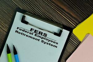 FERS - Federal Employees Retirement System write on a paperwork isolated on Wooden Table. photo