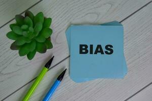 Bias write on sticky notes isolated on Wooden Table. photo